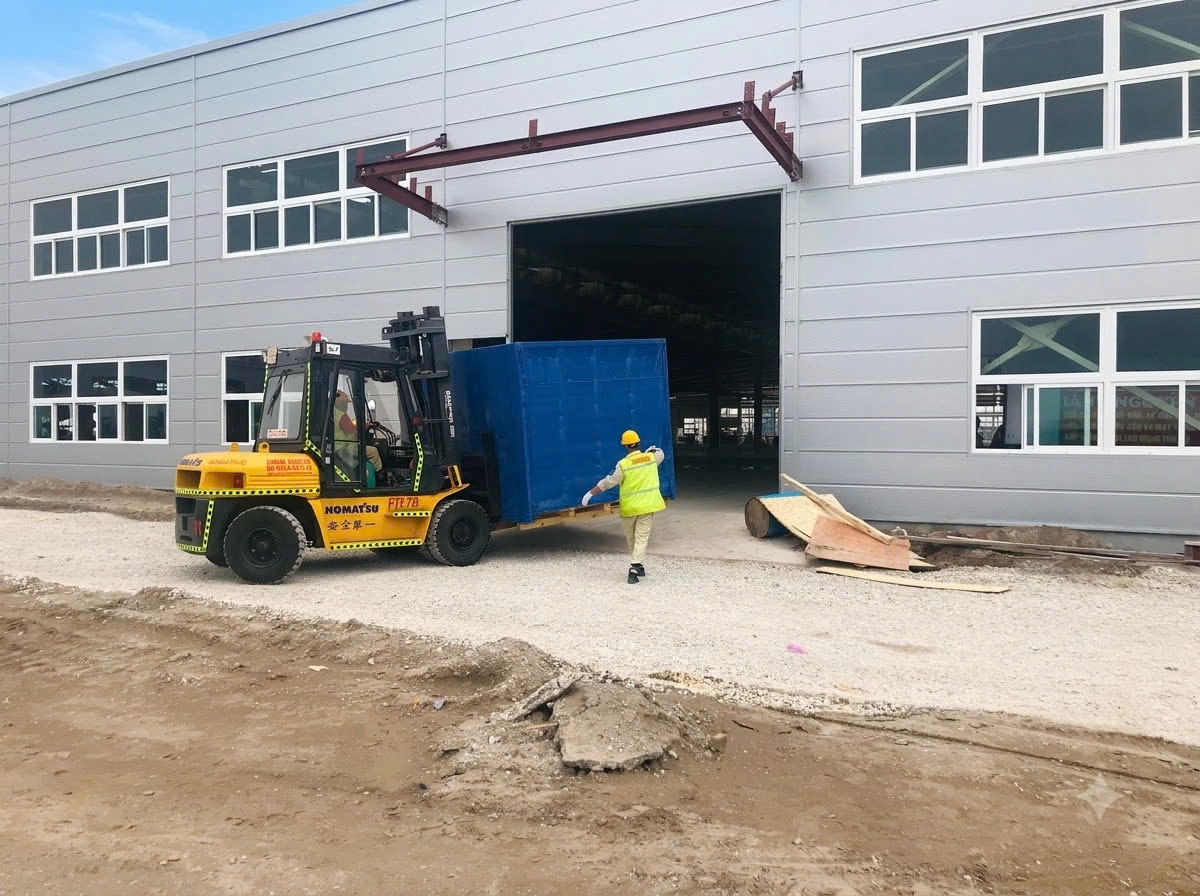 xe nâng Komatsu 7 tấn vận chuyển kiện máy móc luồn qua cửa kho xưởng tiền chế mới tại KCN Tân Trường Hải Dương - THÀNH HUY HOÀNG